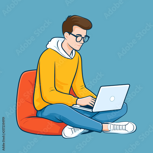 Young man wearing glasses typing on a laptop while sitting cross-legged