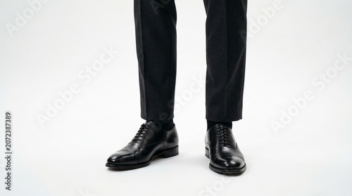 Close up of formal shoes with trousers on a neutral background