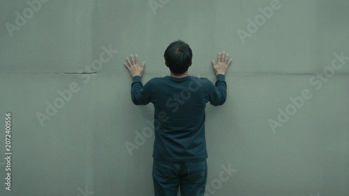 Back View of Man Pressing Hands Against a Grey Concrete Wall