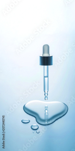 Droplet from a dropper falls onto a clear surface forming a small pool of liquid