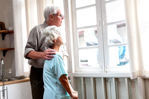 Obraz na plátně Elderly couple gazing outside window.