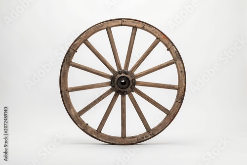 Large wooden wagon wheel with iron rim and spokes, isolated on a white background, showing aged timber texture and traditional construction