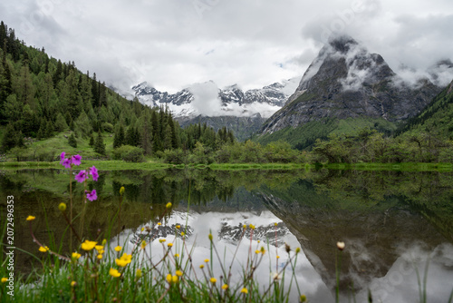 Natural Scenery of Valleys, Lakes, and Forests Beneath Snow-Capped Mountains Shrouded in Clouds and Mist