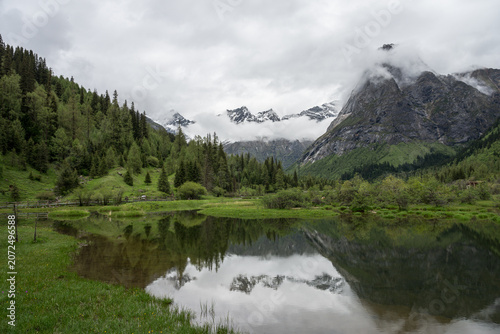 Natural Scenery of Valleys, Lakes, and Forests Beneath Snow-Capped Mountains Shrouded in Clouds and Mist