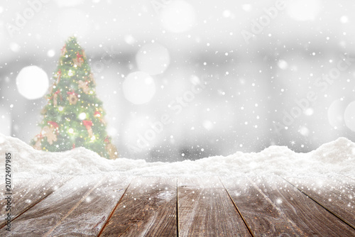 Closeup top wood table with Blur Background and snow christmas time, for your photo montage or product display, Wood table top on blur Christmas tree in snow, Space for placing items on the table.