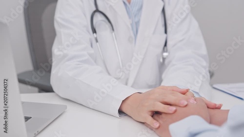 professional doctor holding patient hand to comfort, support, and give reassurance with empathy during a medical consultation and health checkup appointment, focusing on mental health in a clinic