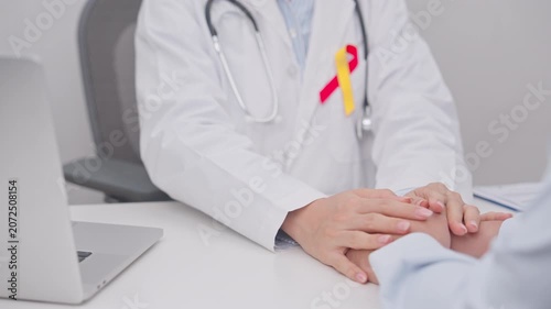 World hepatitis day awareness month, 28 July. doctor holding patient hand to comfort and support with empathy. Red and Yellow ribbon for Liver cancer, Jaundice, Cirrhosis, Failure, Enlarged