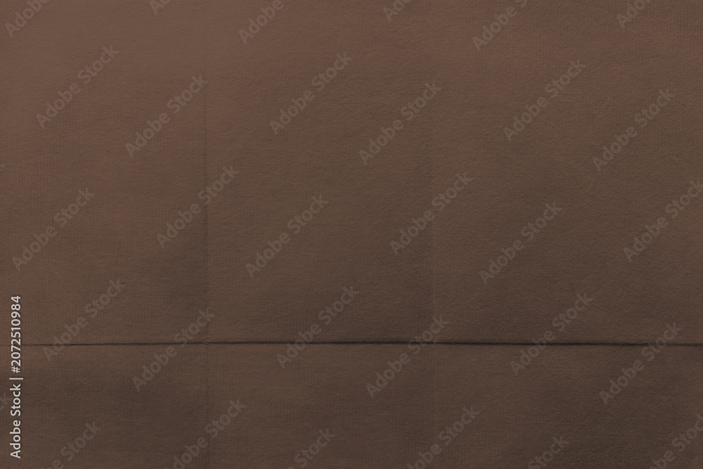 Fototapeta premium Brown textured fabric background with subtle folds and shadows.