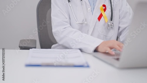 World hepatitis day awareness month, 28 July. doctor using laptop and report notes on notebook. Red and Yellow ribbon for Liver cancer, Jaundice, Cirrhosis, Failure, Enlarged, Hepatic Encephalopathy