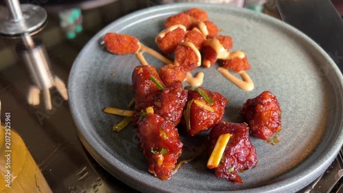 A vibrant platter of spicy Indo-Chinese chilli chicken tossed with bell peppers, paired with golden, crispy deep-fried fish nuggets and dipping sauce.