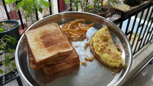 Indian breakfast with bread omelette and sweet jalebi; professional food photography of traditional masala egg omelet, toasted white bread, crispy syrupy dessert, and popular morning street food
