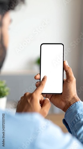 A person holds a blank smartphone screen in a bright room
