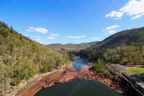 Obraz na płótnie A beautiful high-angle view looking down at a rocky river winding through green hills under a bright blue sky at Somerset Dam in Queensland, Australia
