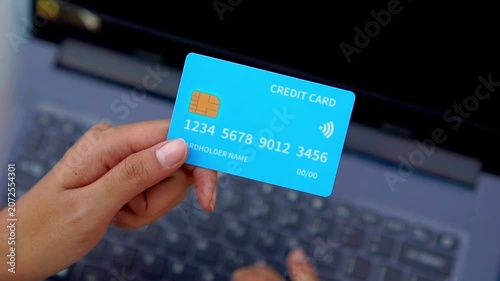 A hand holding a credit card in front of a computer. Illustration for online shopping, online transactions, etc.