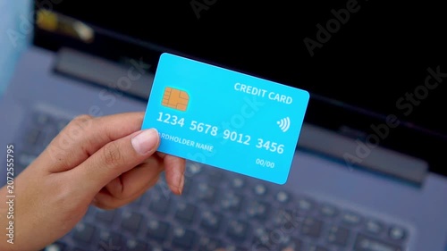 A hand holding a credit card in front of a computer. Illustration for online shopping, online transactions, etc.