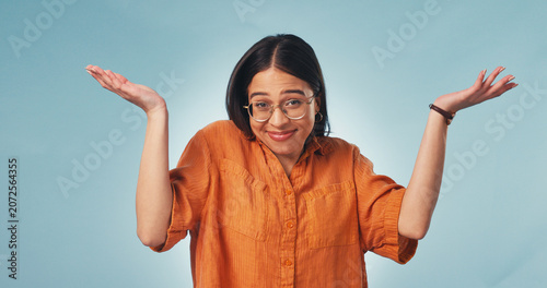 Tableau sur toile Woman, portrait and shrug in studio with smile, clueless and careless with hands raised for opinion