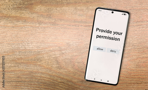 Картината върху платно A smartphone on a table with the text provide your permission and the option to allow or deny