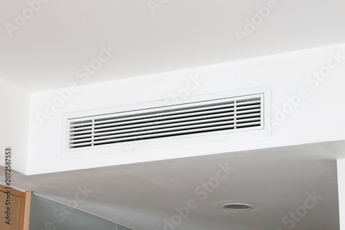 Air Condition (AC) at white ceiling vent with  sleek horizontal slats. Minimalist interior design. Clean lines and modern style. Ideal for home or office settings. Quiet, functional, unobtrusive detai