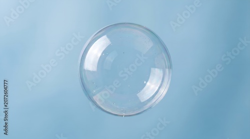 Glistening clear spherical bubble floating gracefully against a serene light blue background
