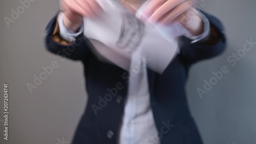 A man in a suit stands against a plain backdrop and demonstrates a motivational act by tearing a sign that reads stagnation