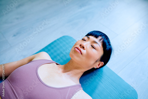 Fotografía Woman lying on a yoga mat, eyes closed, meditating and finding inner peace, embo