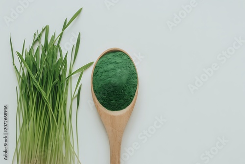 Wheatgrass Powder in Wooden Spoon on White Background