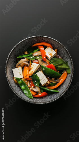 Tofu vegetable stir-fry featuring artisan minimalist plating with meticulously arranged bell pepper and snap pea.