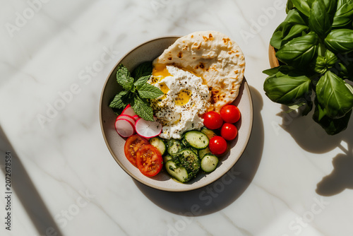 Sabzi khordan platter with a minimalist presentation of creamy cheese, rustic flatbread, and crisp raw vegetables