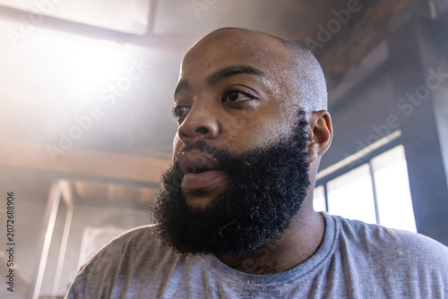 Bild auf Leinwand African American man breathing heavily while standing in warehouse wearing grey