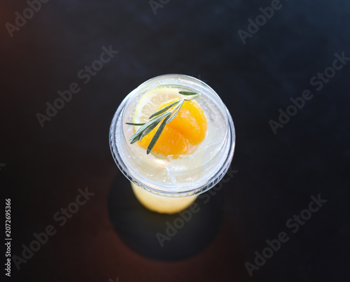 Cold orange soda in a plastic glass against a black background.