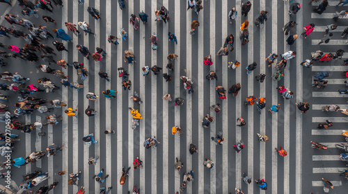 Aerial view of busy urban pedestrians crossing a street with zebra lines, showcasing daily city life dynamics.