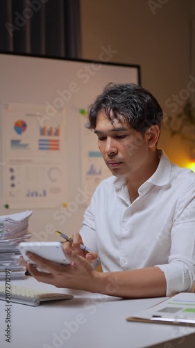 Stressed asian businessman working overtime at night in the office