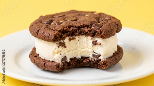 Bitten Chocolate Chip Ice Cream Sandwich on White Plate and Yellow Background