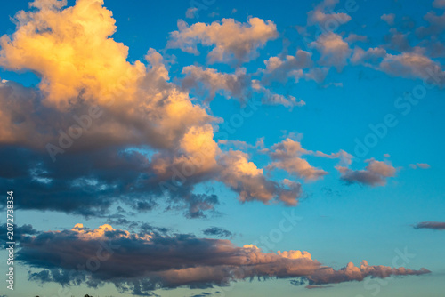 Fotografie Open sky with layered glowing clouds in vibrant blue atmosphere shows playful su