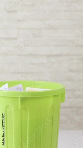 Throwing money into trash bucket