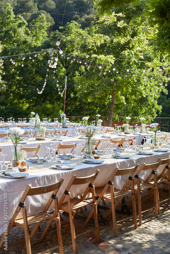 Obraz premium Vertical View of Outdoor Wedding Reception with Long Banquet Tables and String Lights