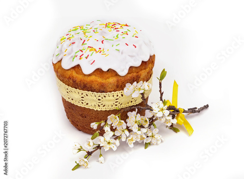 Festive Cake With White Icing and Colorful Sprinkles Next to Flower Branch on Plain Background