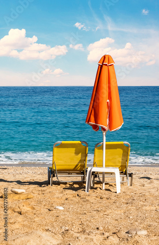 orange beach umbrellas and sunbeds on sandy mediterranean beach