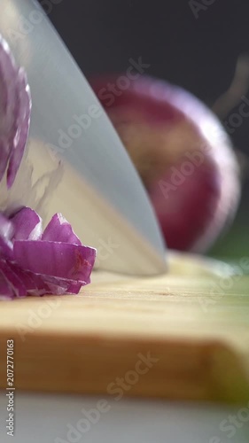 Camera movement on hands cut red onion on wooden cutting board in kitchen. Choping. Cooking food. Vertical shot