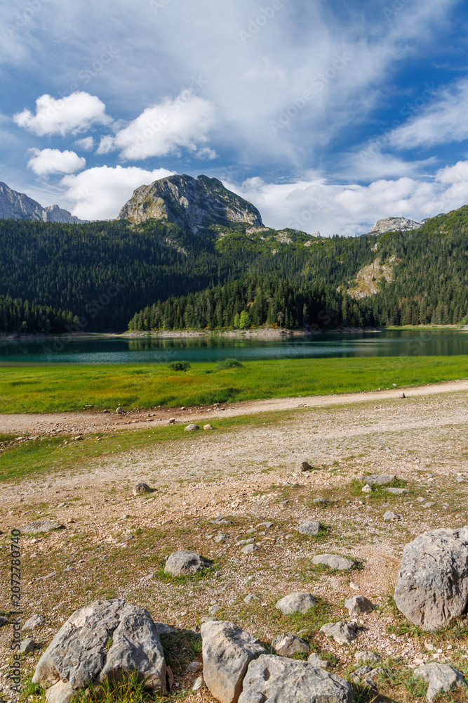 Obraz premium Calm lake with forest reflection under blue sky
