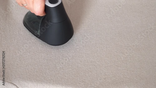 Top view hand removes pills from woolen knitted clothing using fabric shaver. Textile pilling. Linting. Fabric lint, pilly, pellet, fluff