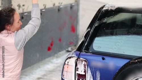 This captivating video shows a woman washing her blue car at a self-service car wash. The playful splashes and sparkling suds beautifully showcase the fun of maintaining a clean vehicle. Slow motion