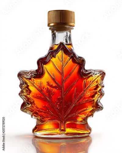 Glass bottle with autumn maple leaf design filled with golden liquid on reflective surface