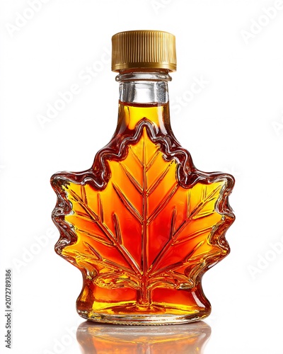 Glass bottle with autumn leaf design filled with golden liquid on reflective surface