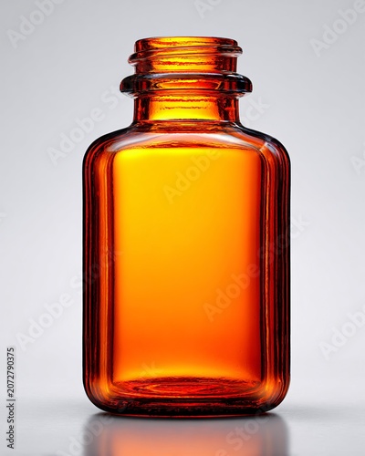 Amber glass bottle with golden liquid and metal cap on reflective surface