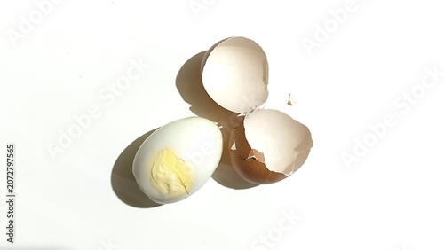 Fotografía top view of a completely peeled hard boiled egg with two broken brown eggshell h