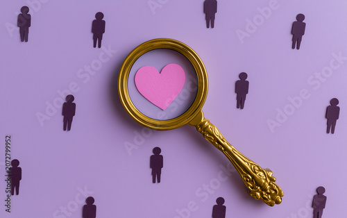 Search for love and dating. Magnifying glass finds the heart of love among the candidates. Matchmaking in online dating. Relationship building. Couple for February 14th.