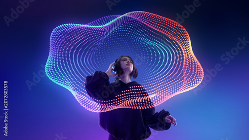 Canvas-taulu Young woman listening to headphones under colorful digital sound wave mesh