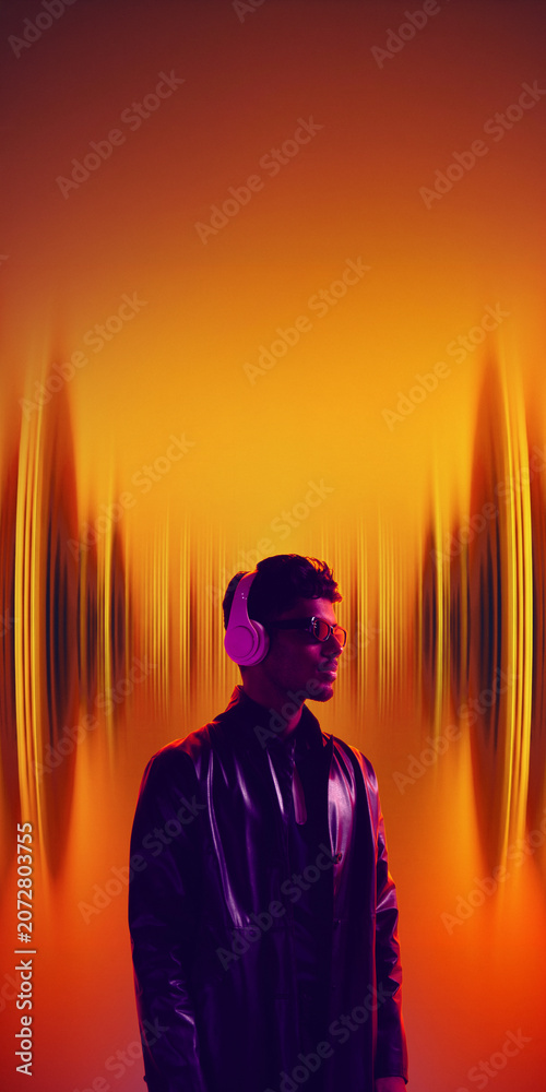 Fototapeta premium Young man with headphones and sunglasses between glowing orange sound waves. Concept of music streaming service, club audio promo, podcast platform and electronic music poster.