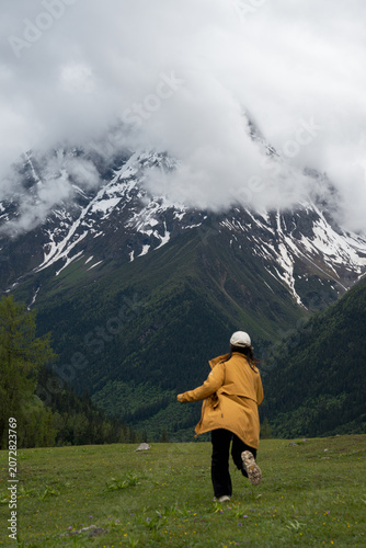 The female traveler runs toward the snow-capped mountains